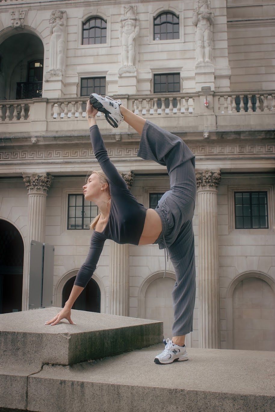 Viktoriia in a one-arm balance outside a columned London building
